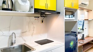 Moderni keittiö, jossa on keltaiset kaapit, ruostumattomasta teräksestä valmistettu pesuallas, kahvinkeitin ja mikroaaltouuni.