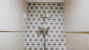 Shower area features a unique tile design and a mounted showerhead with a control panel.
