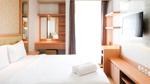 Relax in a spacious room with a large bed, flat-screen TV, and modern vanity.