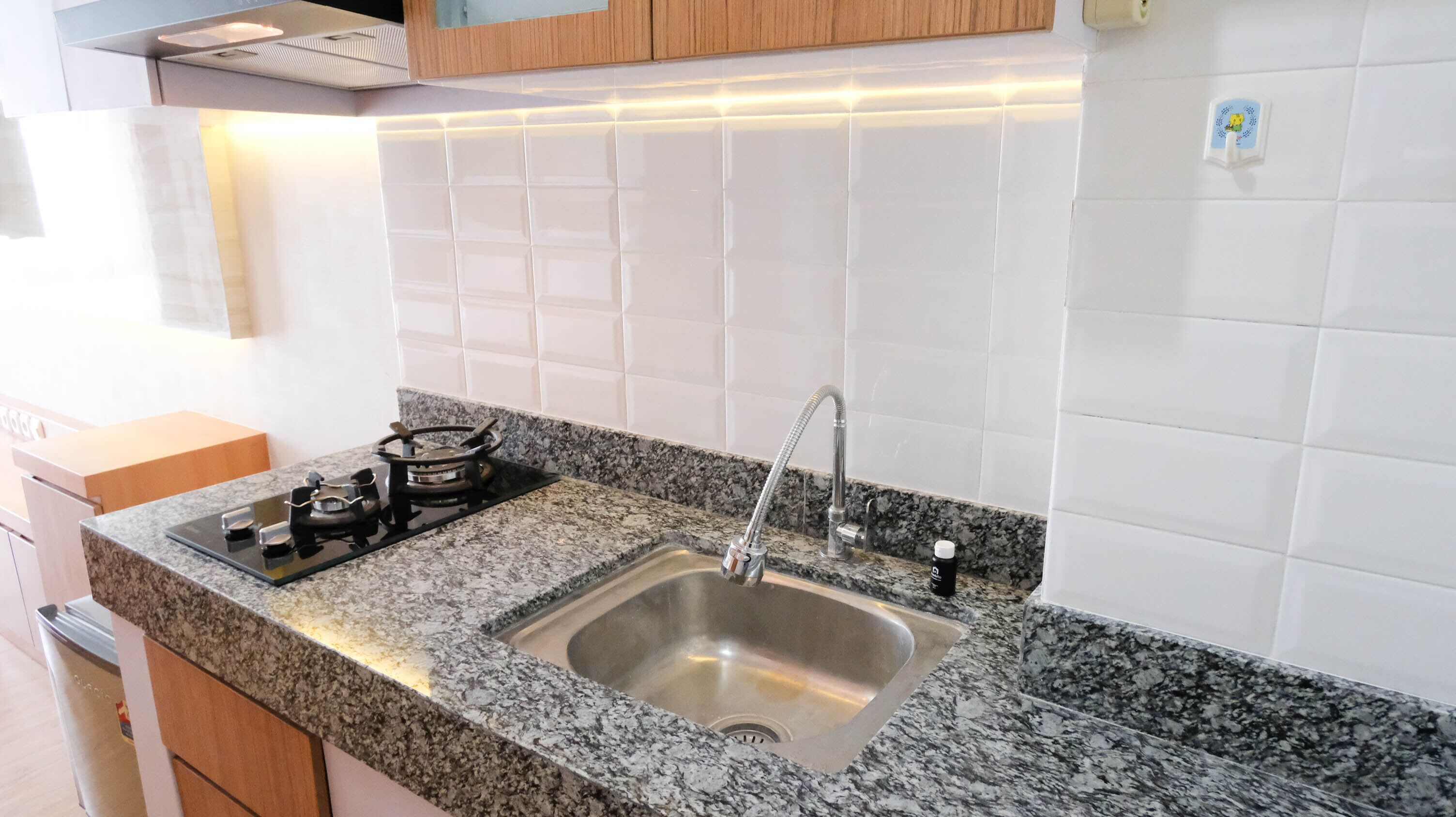 A kitchen with a granite countertop, stainless steel sink, and a gas stove.