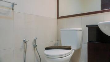 A bathroom with a toilet, a shower, and a sink.
