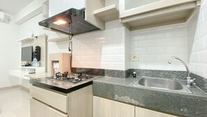 A modern kitchen with a gas stove, stainless steel sink, and white subway tiles.