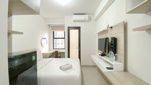 A hotel room with a bed, a TV, a desk, and a window.