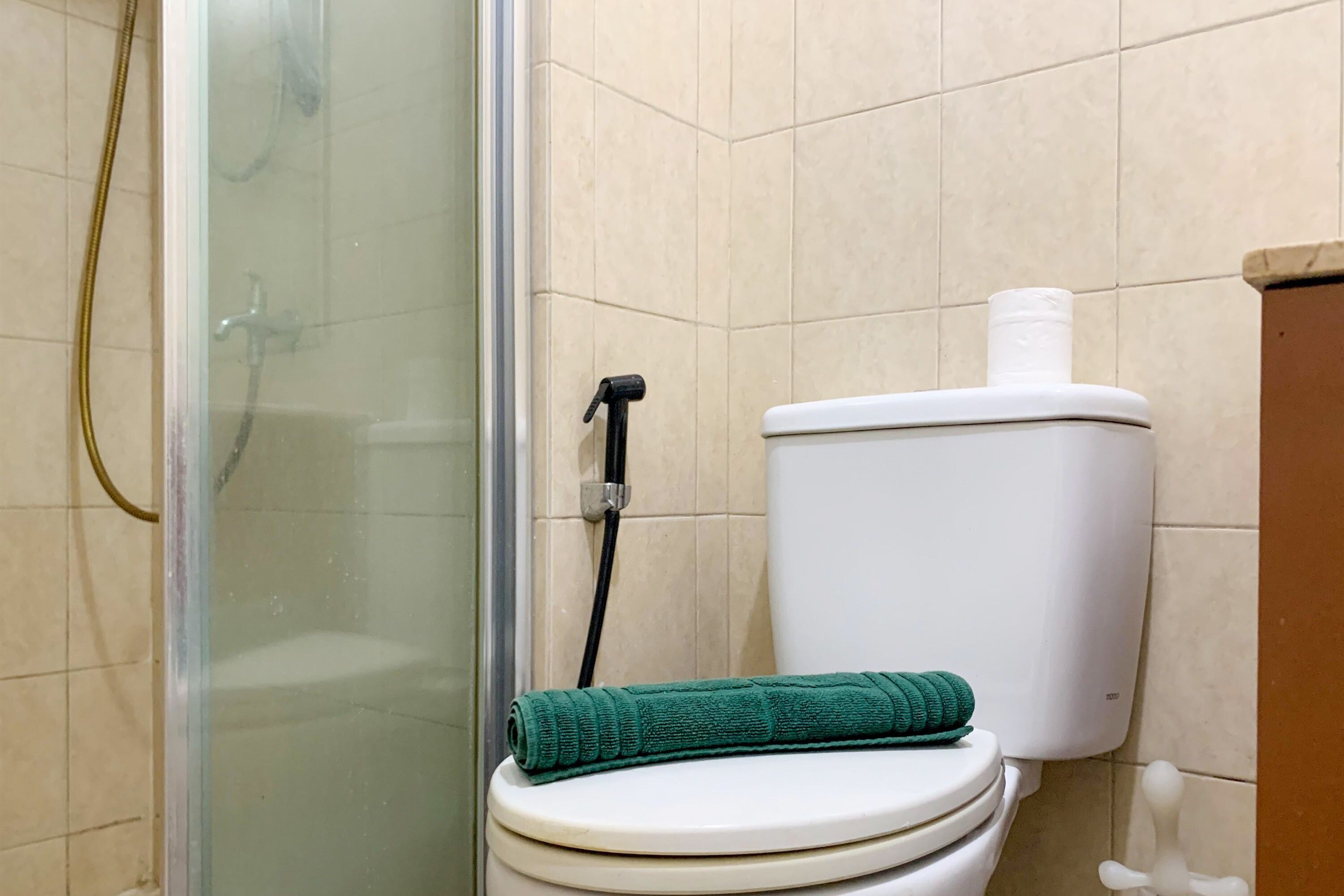 Ein Badezimmer mit Toilette, Dusche und Handtuch auf der Toilette.