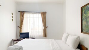 A hotel room with a bed, a desk with a computer, and a window with curtains. - Comfortable And Homey 3Br At Marina Ancol Apartment (Jakarta)