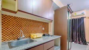 Uma cozinha com painel de fundo xadrez, pia, armários e janela com cortina.