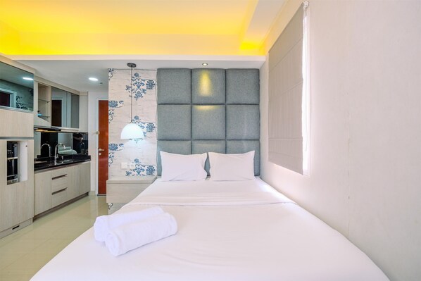 Relax in a stylish room with a large bed, kitchen, and elegant wall decor.