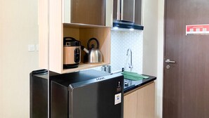 A compact kitchen with a black refrigerator, a kettle, and a sink. - Modern Look And Homey Studio Apartment At Transpark Juanda Bekasi Timur (Bekasi)