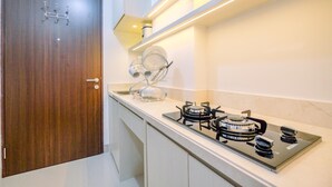 A modern kitchen with a built-in stove, a dish rack, and a wooden door. - Comfy And Elegant Studio Transpark Cibubur Apartment (Depok)