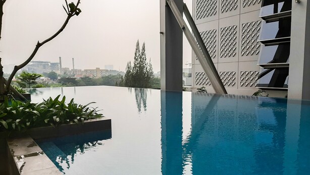 An infinity pool with a clear view of the city skyline in the background. - Nice And Cozy Studio At Paddington Heights Apartment (Tangerang)