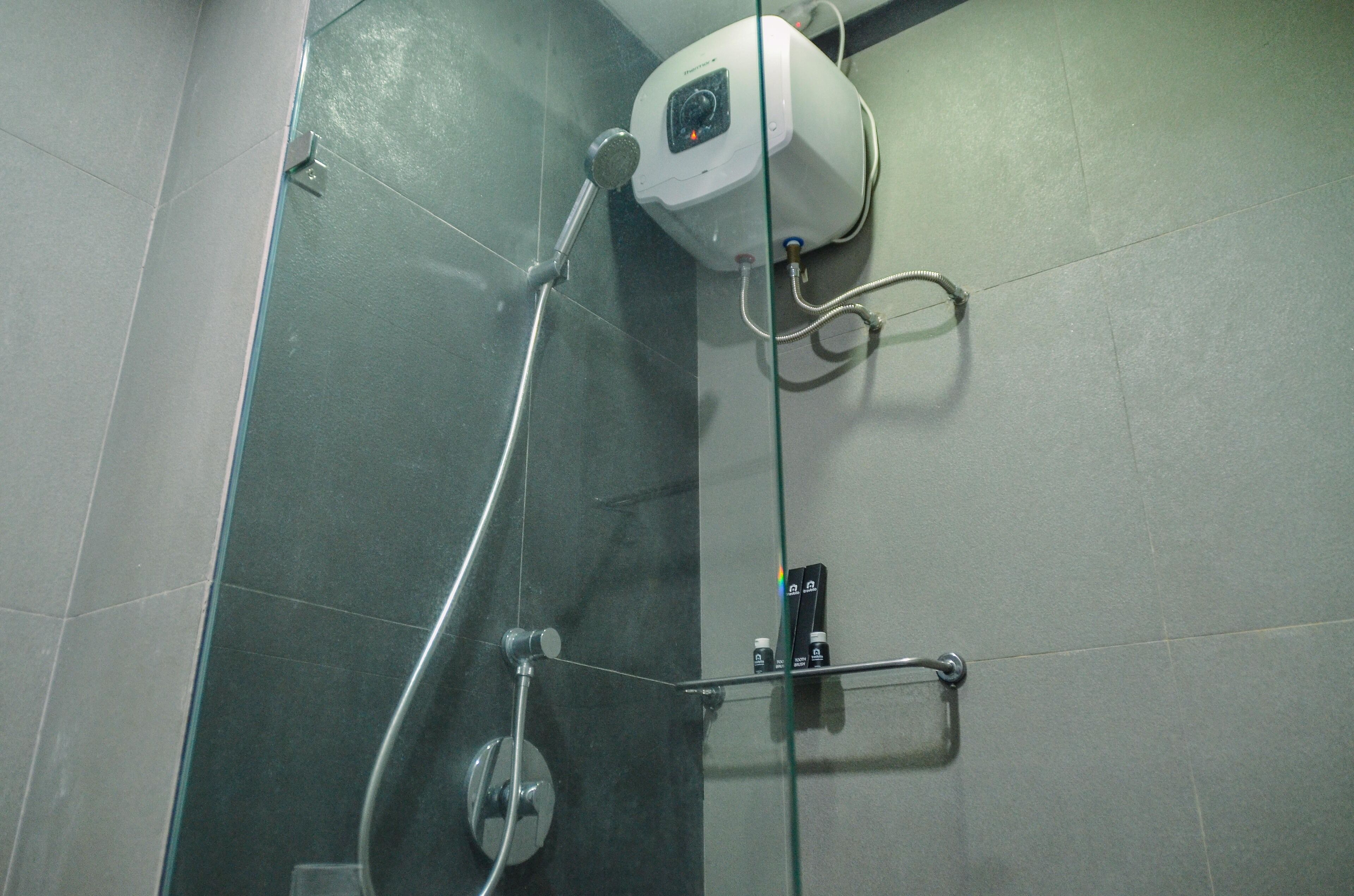 A shower with a glass enclosure, a handheld showerhead, and a control panel.