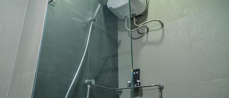 A shower with a glass enclosure, a handheld showerhead, and a control panel.
