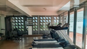 A gym with treadmills, exercise equipment, and large windows offering views of the outdoors. - Nice And Cozy Studio At Paddington Heights Apartment (Tangerang)
