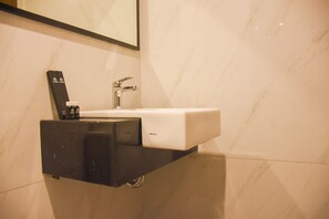 Bathroom features a sleek sink, faucet, and soap dispenser, set against a minimalist backdrop.
