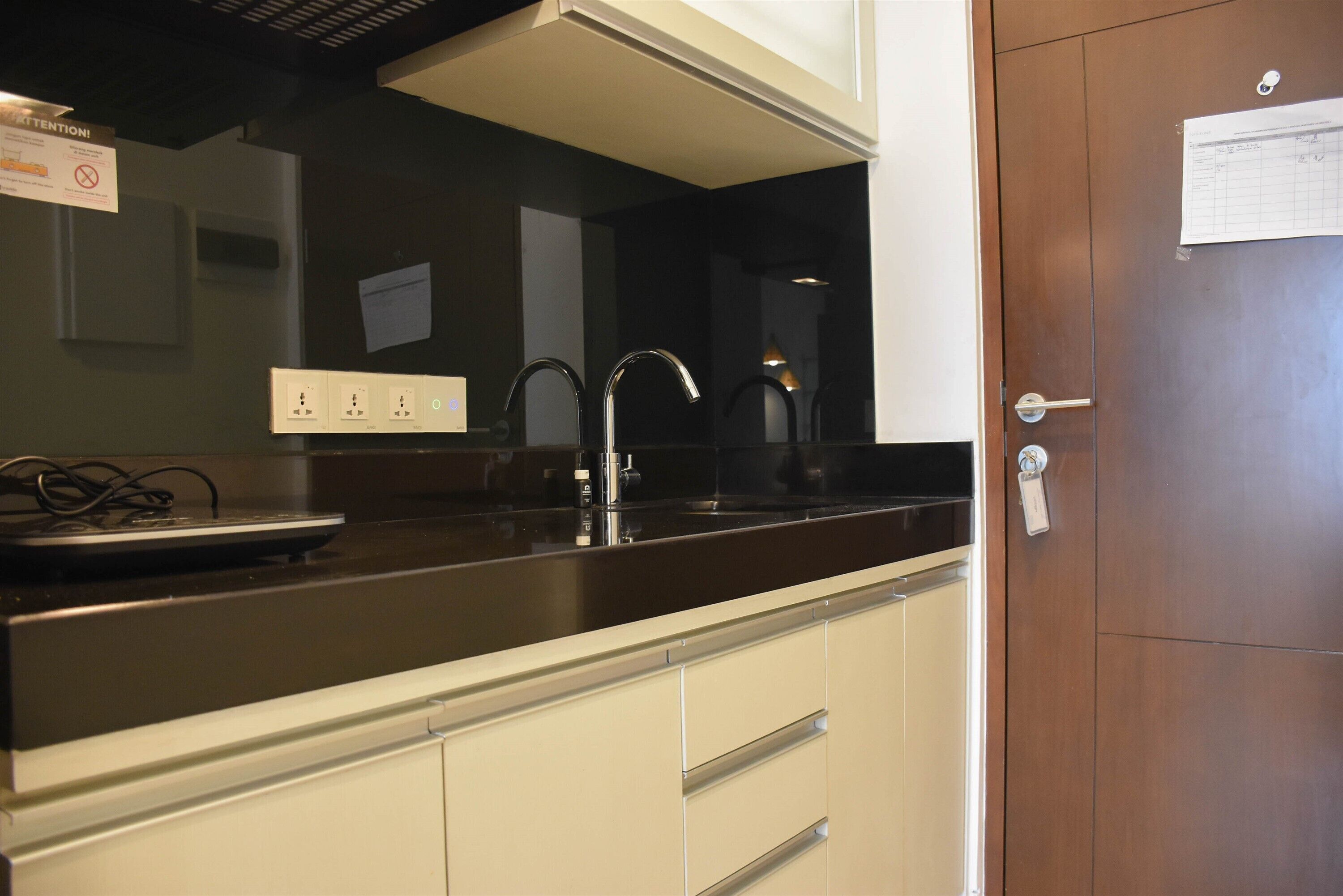 A kitchen with a black countertop, white cabinets, and a stainless steel sink.