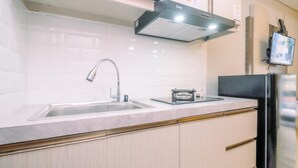 A modern kitchen with a stainless steel sink, a built-in stove, and a refrigerator. - Modern Look Studio Lrt City Sentul - Royal Sentul Park Apartment (Bogor)