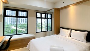 Una camera d'albergo con un letto, una scrivania e una finestra che dà su un edificio e del verde.