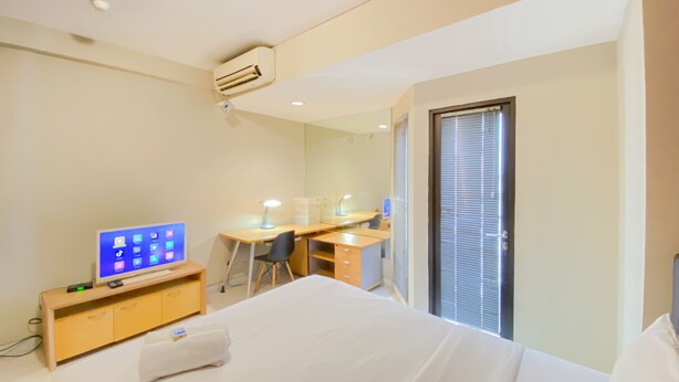 Hotellihuone, jossa on sänky, työpöytä, tuoli, televisio ja ikkuna, jossa on sälekaihtimet.