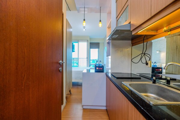 A modern kitchen with wooden cabinets, a black countertop, a stainless steel sink, and pendant lighting.