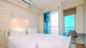 A hotel room with a large bed, a desk, and a view of the city through a window. - Minimalist Studio With Great City View At Tifolia Apartment (Jakarta)