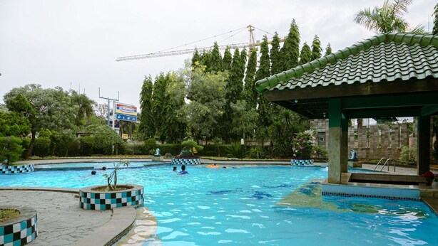 A swimming pool with checkered borders, surrounded by trees and a covered pavilion. - Cozy And Simply Look 2Br At 12Nd Floor Puri Garden Apartment (Jakarta)