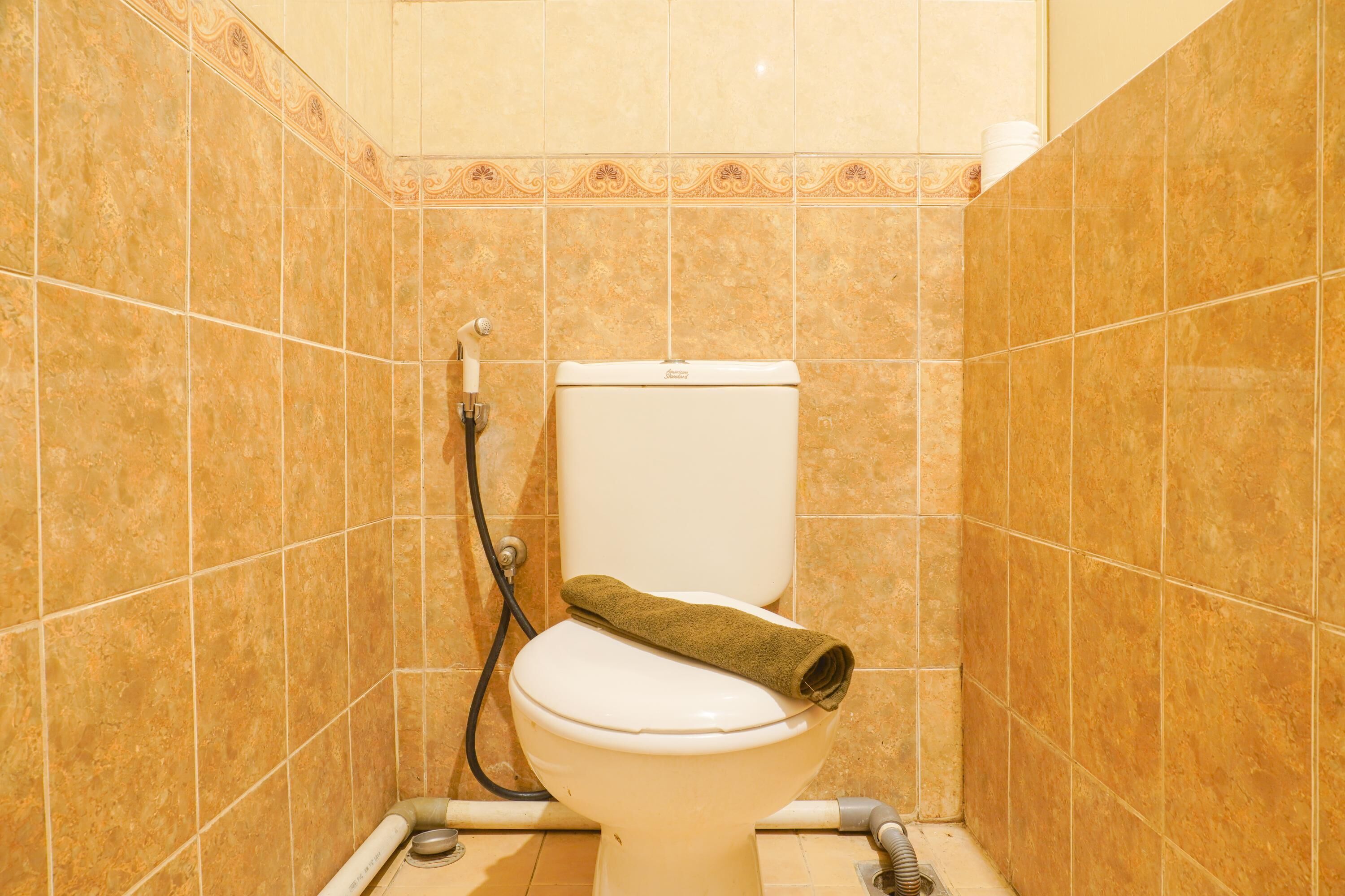 Une salle de bain avec des toilettes, une serviette et un tuyau.