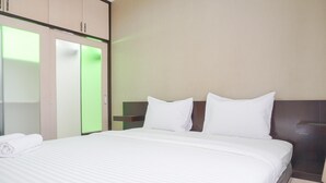 A hotel room with a large bed, a wardrobe with a mirror, and a bedside table. - Cozy And Simply Look 2Br At 12Nd Floor Puri Garden Apartment (Jakarta)