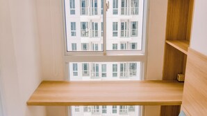 A room with a large window, wooden shelves, and a view of a building with balconies. - Comfy Studio At 30Th Floor Tokyo Riverside Pik 2 Apartment (Teluknaga)