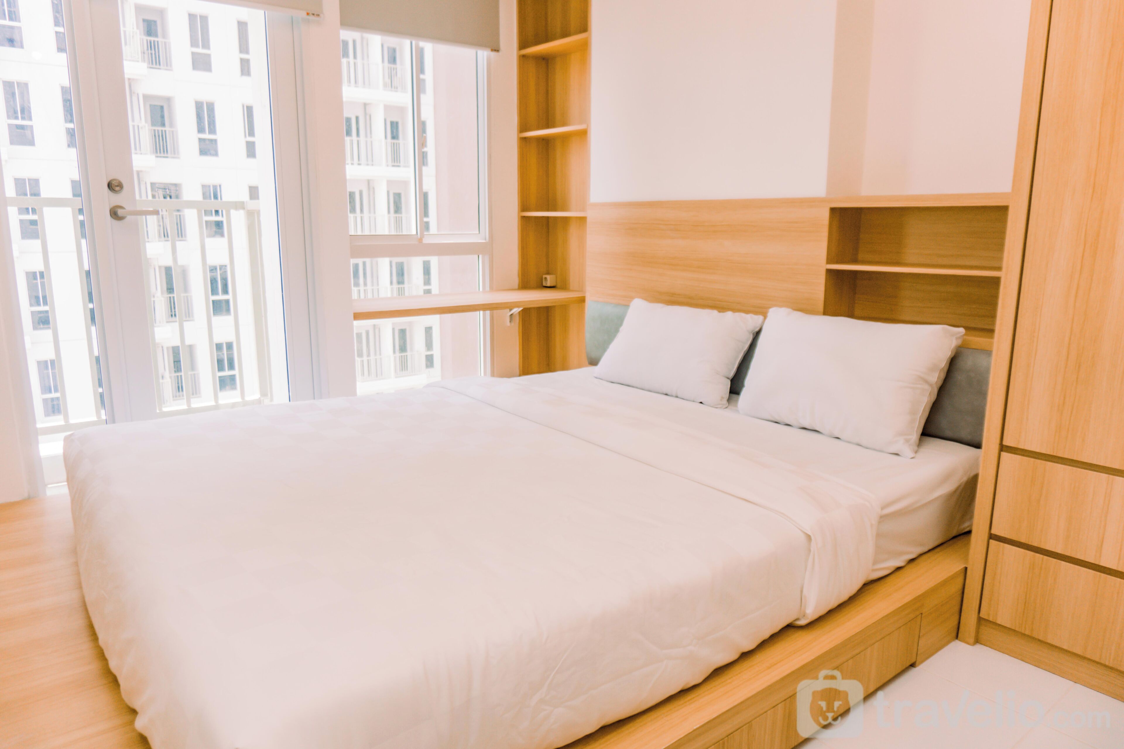 Een moderne slaapkamer met een groot bed, inbouwplanken en uitzicht op de stad door een geopende deur.