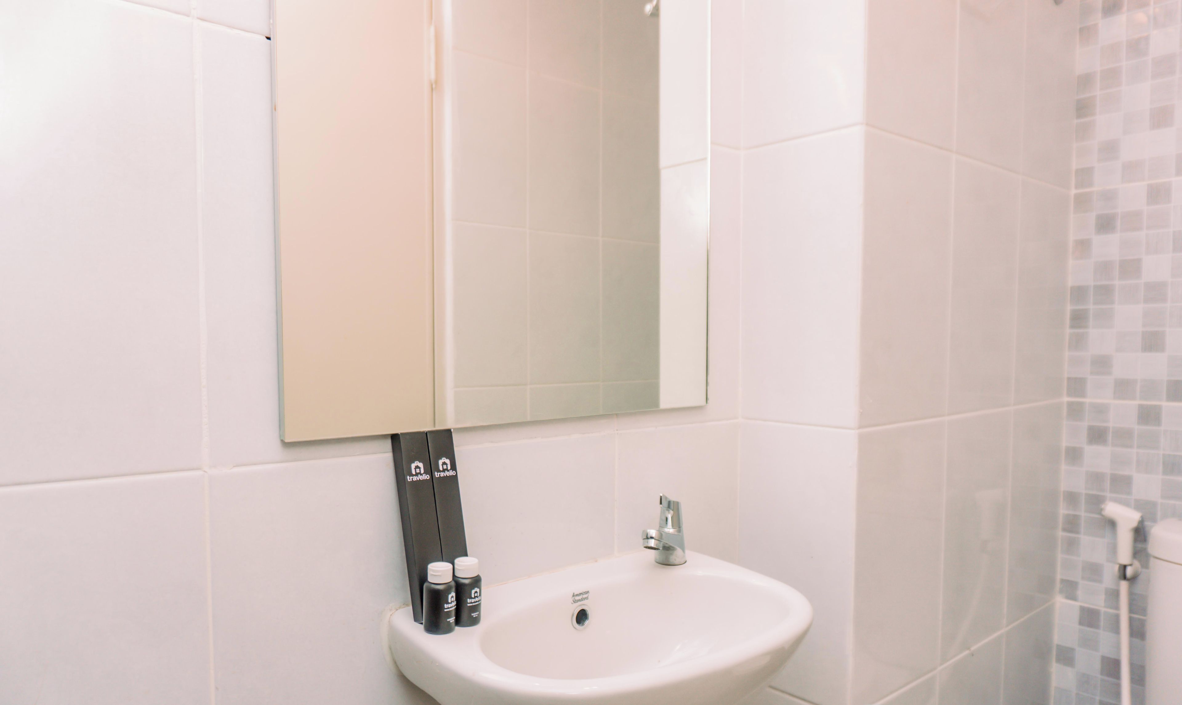 A bathroom with a white sink, a mirror, and a tiled wall.