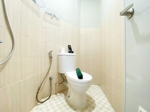 A small, clean bathroom with a toilet, a shower, and a towel rack.