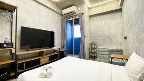 A modern hotel room with a large bed, a flat-screen TV, a minibar, and a view of the outdoors. - Fully Furnished And Homey Studio Grand Kamala Lagoon Apartment (Bekasi)