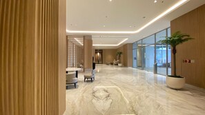 Um hall amplo com piso de mármore, área de estar e balcão de recepção.