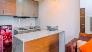 A modern kitchen with wooden cabinets, a granite countertop, and a stainless steel sink. - Nice And Comfort 2Br Apartment At Transpark Cibubur (Depok)