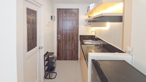 A compact kitchen with a wooden door, a black countertop, and a built-in oven.