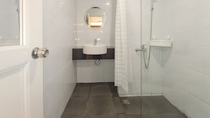 A modern bathroom with a white sink, mirror, and glass shower enclosure.