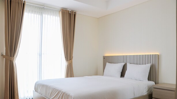 A modern bedroom with a large bed, a bedside table, and a headboard with built-in lighting.