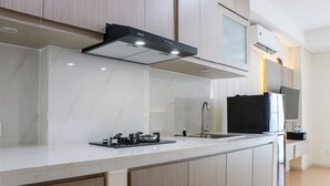 A modern kitchen with light wood cabinets, a stainless steel range hood, and a built-in oven.