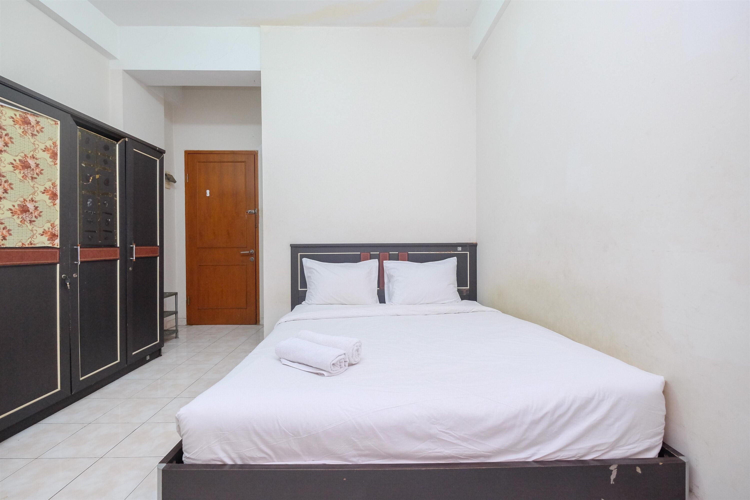A neatly arranged bedroom with a bed, a wardrobe, and a door.