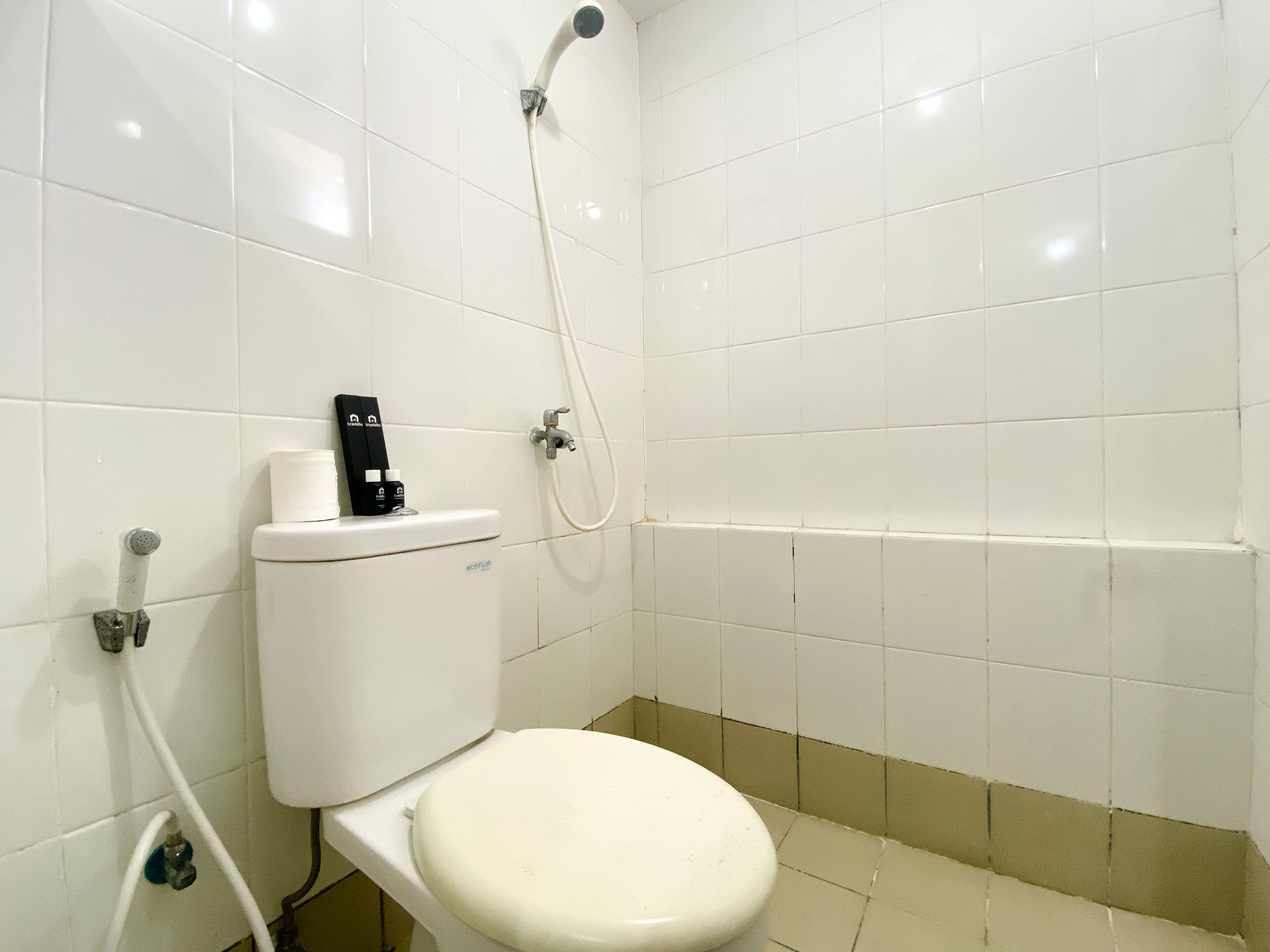 A small, clean bathroom with a toilet, a shower, and a toilet paper holder.
