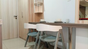 Eine kleine Küchenzeile mit einer Holzausziehtafel, zwei weißen Stühlen und einem Spiegel über der Arbeitsfläche.