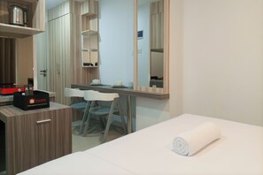 Een hotelkamer met een bed, een bureau met stoel, een kledingkast en een spiegel.