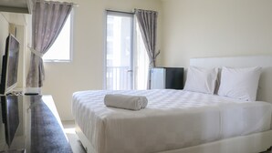 Une chambre d’hôtel avec un grand lit, un téléviseur à écran plat, un bureau et des rideaux aux fenêtres.