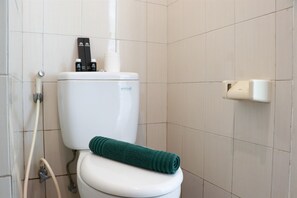 A standard bathroom with a toilet, towel, and toilet paper dispenser.