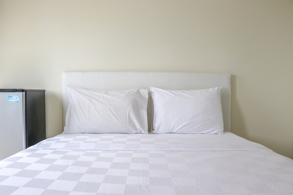 Cozy retreat with a neatly made bed and a refrigerator for your convenience.