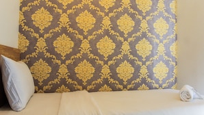 A hotel room with a bed, a pillow, and a rolled towel.