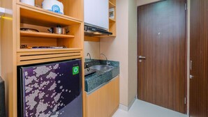 Una cocina compacta con armarios de madera, horno empotrado, lavamanos y refrigerador.