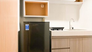 A compact kitchen with a black refrigerator, a built-in sink, and wooden cabinets. - Cozy Stay And Tidy 1Br The Alton Apartment (Semarang)