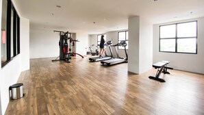 A spacious gym with wooden flooring, treadmills, and weight machines. - Cozy Stay And Tidy 1Br The Alton Apartment (Semarang)