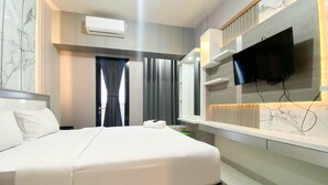 A modern hotel room with a large bed, a flat-screen TV mounted on the wall, and a built-in shelf with lighting. - Cozy Stay And Tidy 1Br The Alton Apartment (Semarang)